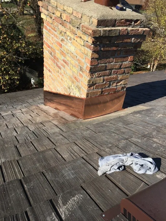 Brick chimney with new copper flashing let into a cedar shake roof