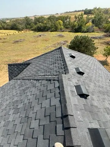 New gray shingle roof on a country property with open fields behind it