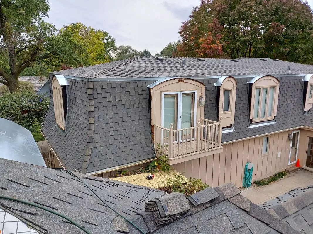 Mansard roof and arched dormer windows finished in new gray shingles