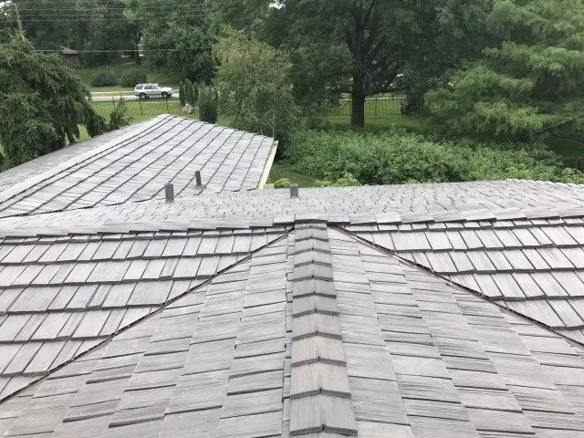 New cedar shake roof meeting at the ridge with trees behind it