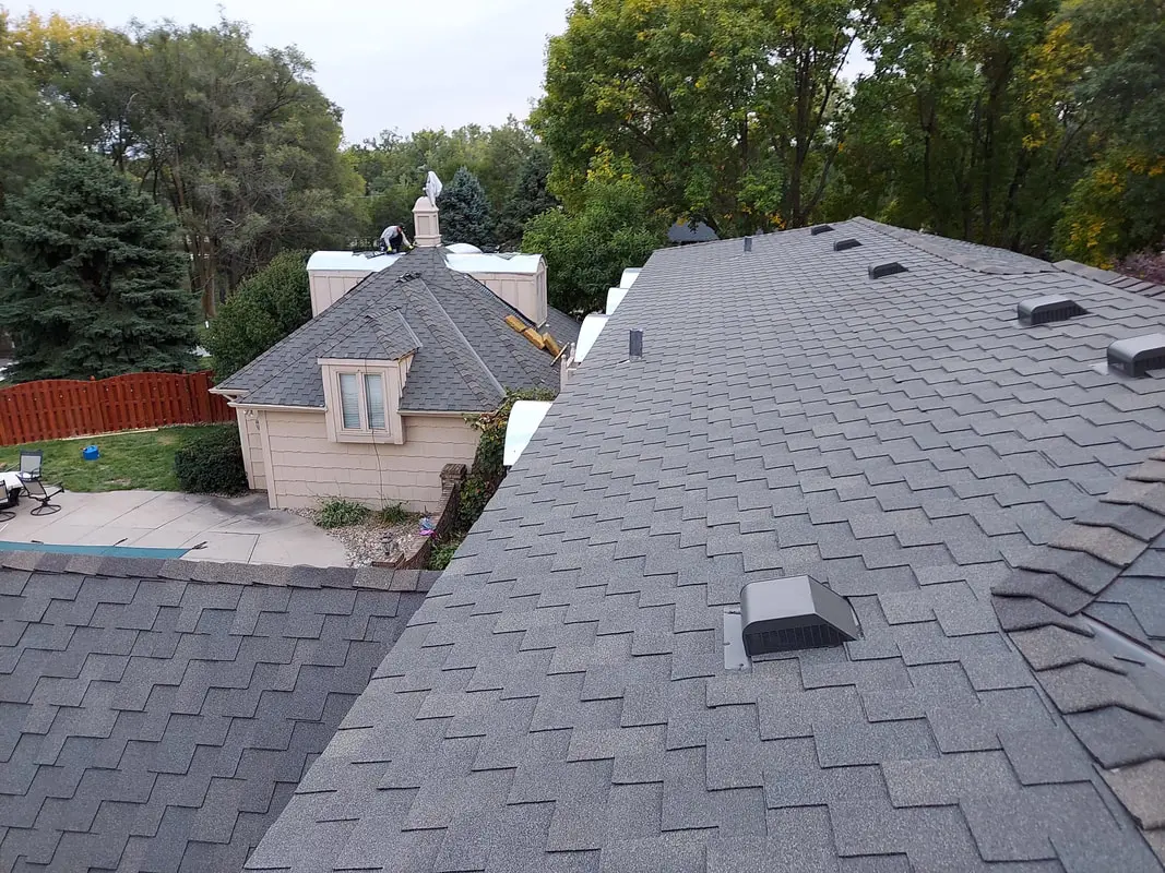 Gray architectural shingle roof photographed from above with vents and a chimney